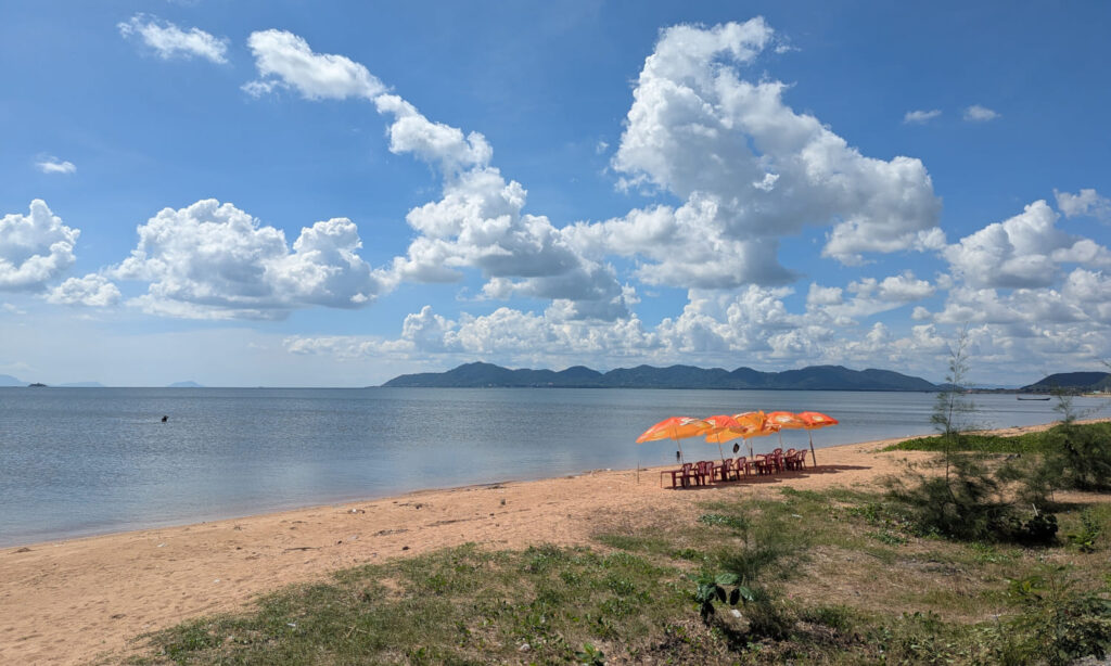Einsamer Strand mit ein paar Stühlen und Sonnenschirmen in Kep, Kambodscha.