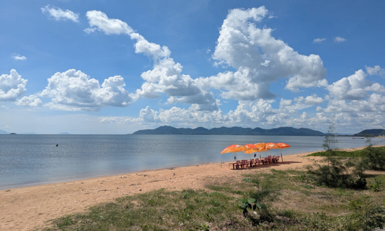 Einsamer Strand mit ein paar Stühlen und Sonnenschirmen in Kep, Kambodscha.