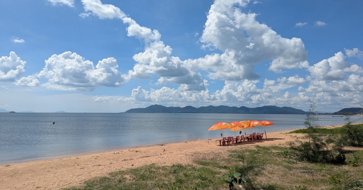 Einsamer Strand mit ein paar Stühlen und Sonnenschirmen in Kep, Kambodscha.